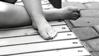 Women's feet on a park bench.
